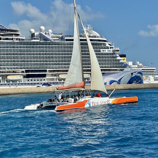 Bolador catamaran sailing past a cruise ship